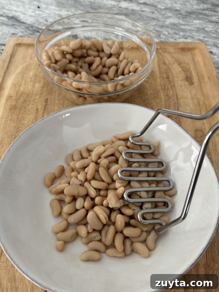 One-Pot White Bean and Sausage Soup 4 Mashing cannellini beans with potato masher.
