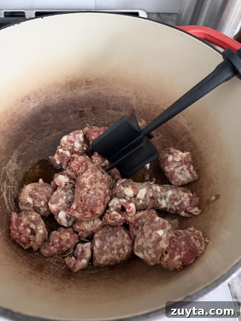 One-Pot White Bean and Sausage Soup 6 Sautéing Italian sausage in Dutch oven while breaking it up with kitchen tool.