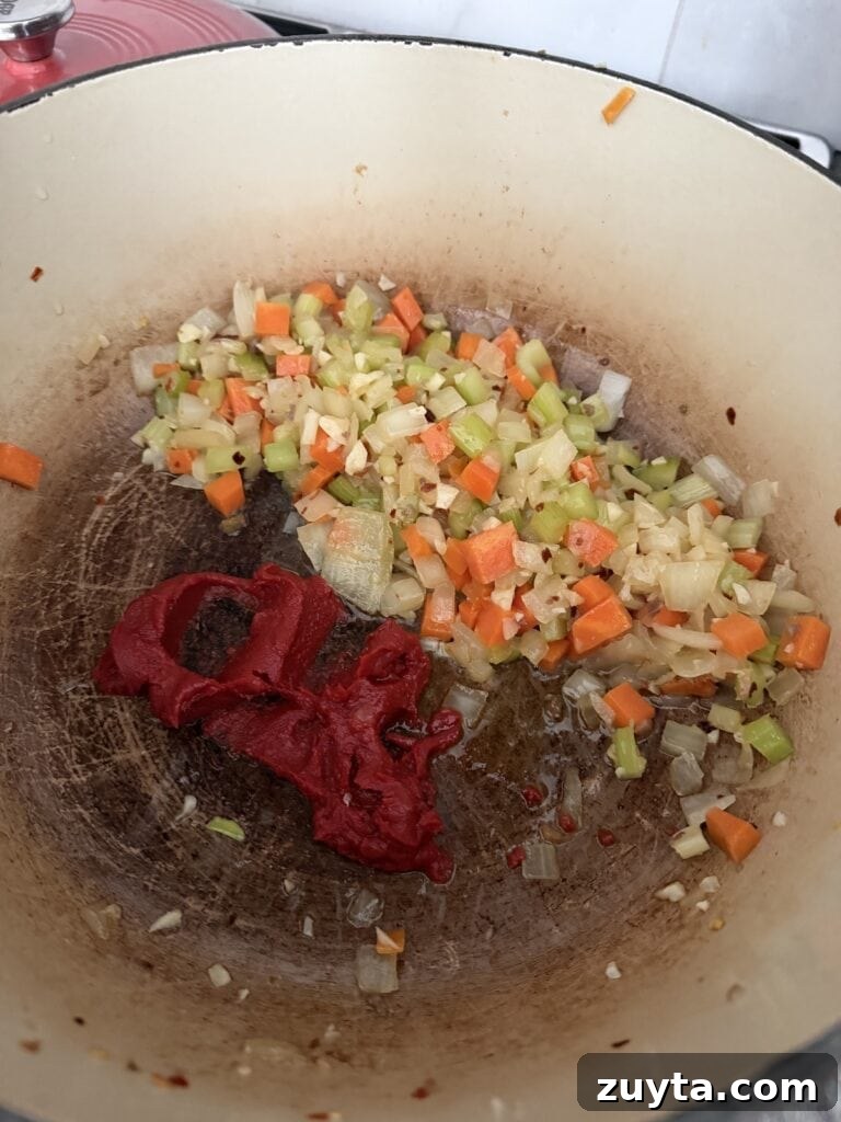 One-Pot White Bean and Sausage Soup 7 Caramelizing tomato paste in pot with vegetables.