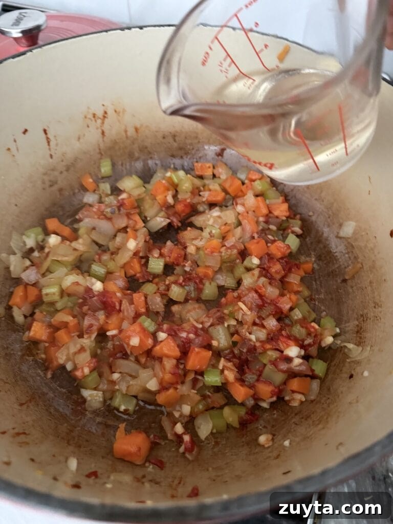 One-Pot White Bean and Sausage Soup 8 Adding white wine to the pot.