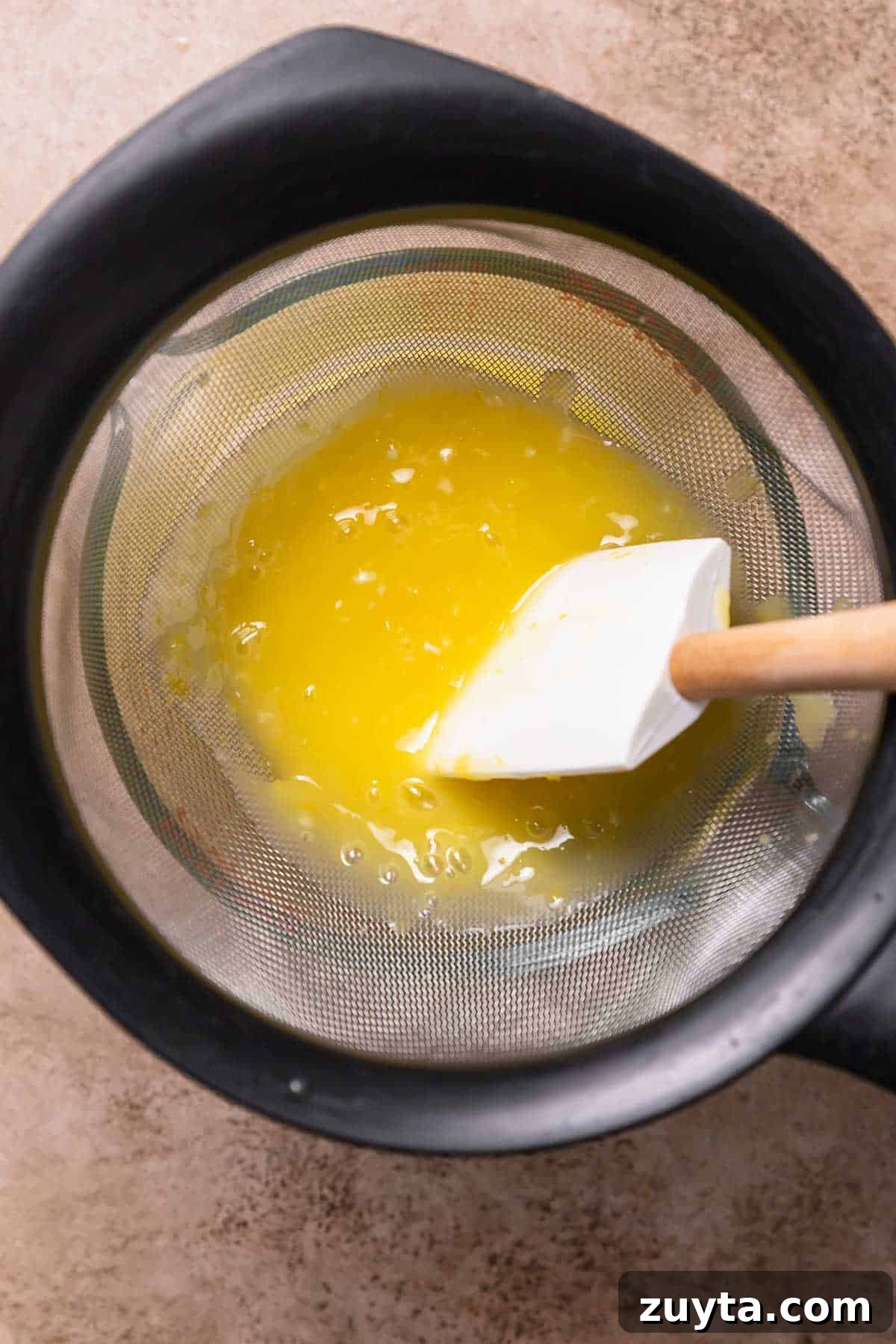 Lemon Curd Recipe: Homemade, Smooth, Zesty 5 Lemon curd being pushed through a fine mesh strainer.