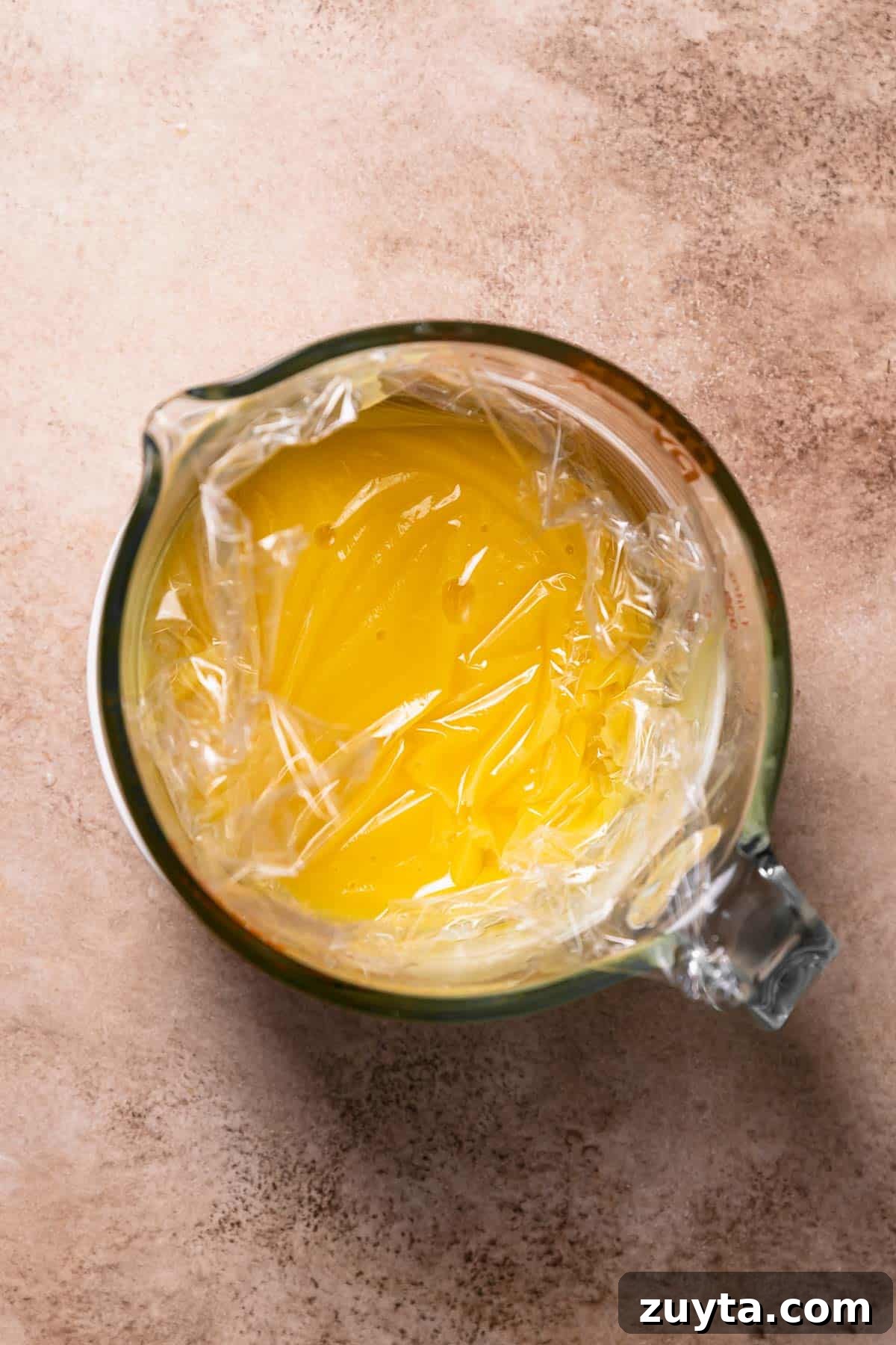 Lemon Curd Recipe: Homemade, Smooth, Zesty 7 A glass bowl with the lemon curd and plastic wrap touching the top surface.