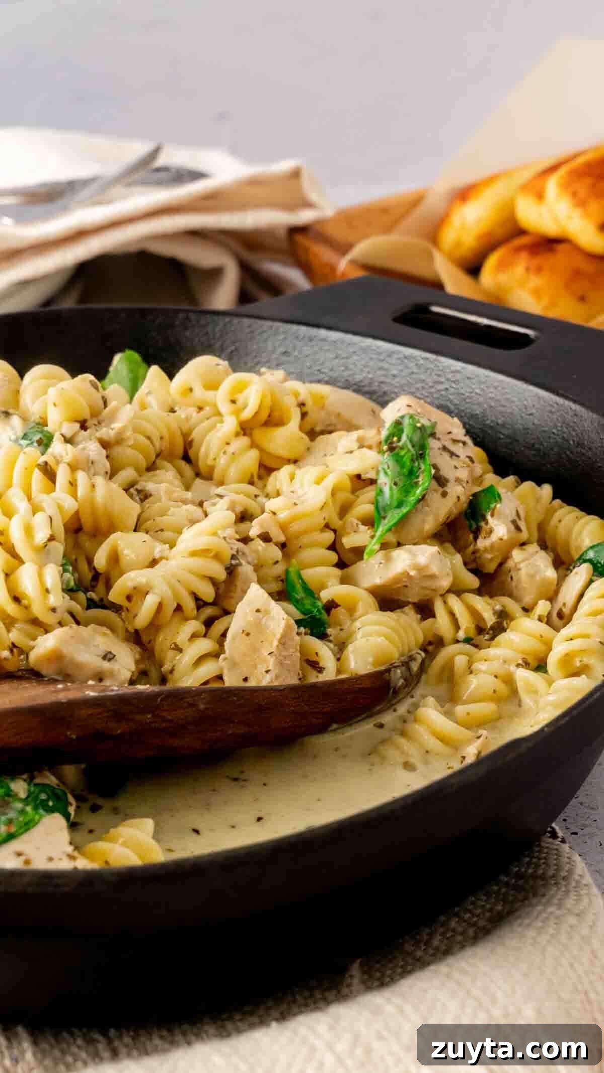 Instant Pot Creamy Pesto Chicken Pasta 4 Instant Pot Chicken Pesto Pasta in a creamy broth served with a wooden spoon.