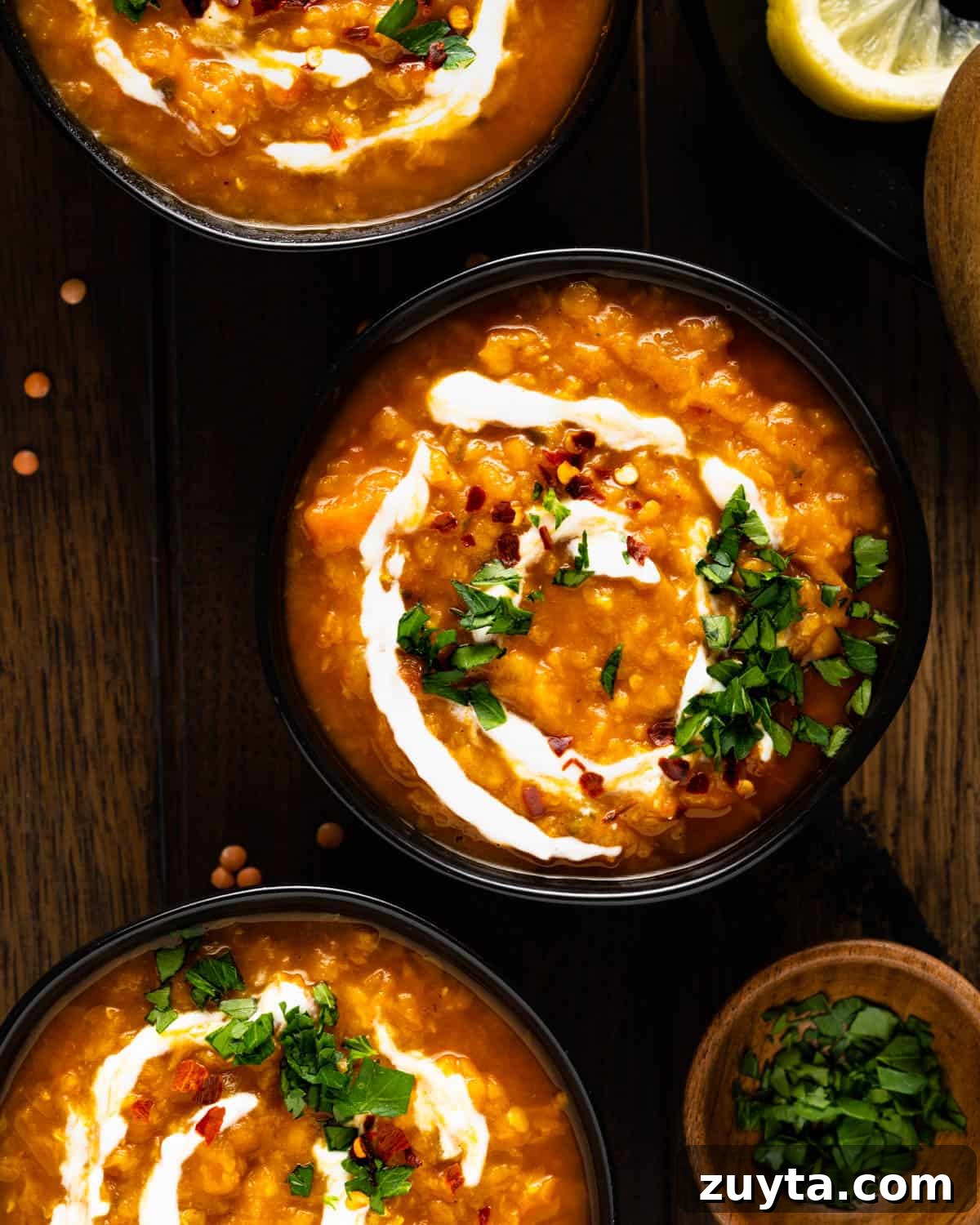 Three bowls of lentil soup garnished with yogurt and cilantro