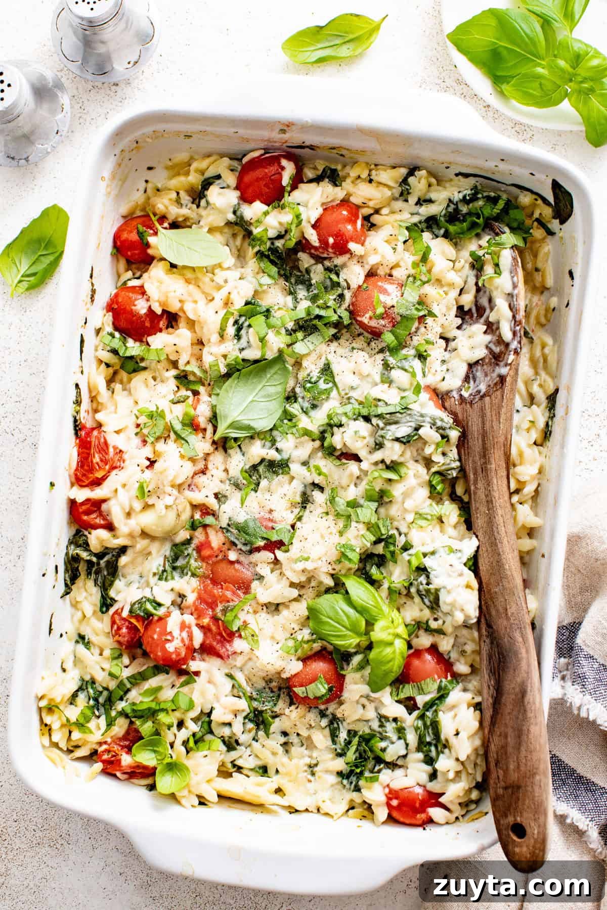 Creamy Boursin Orzo Bake Recipe 8 A Boursin orzo bake with fresh basil on top in a white casserole dish.