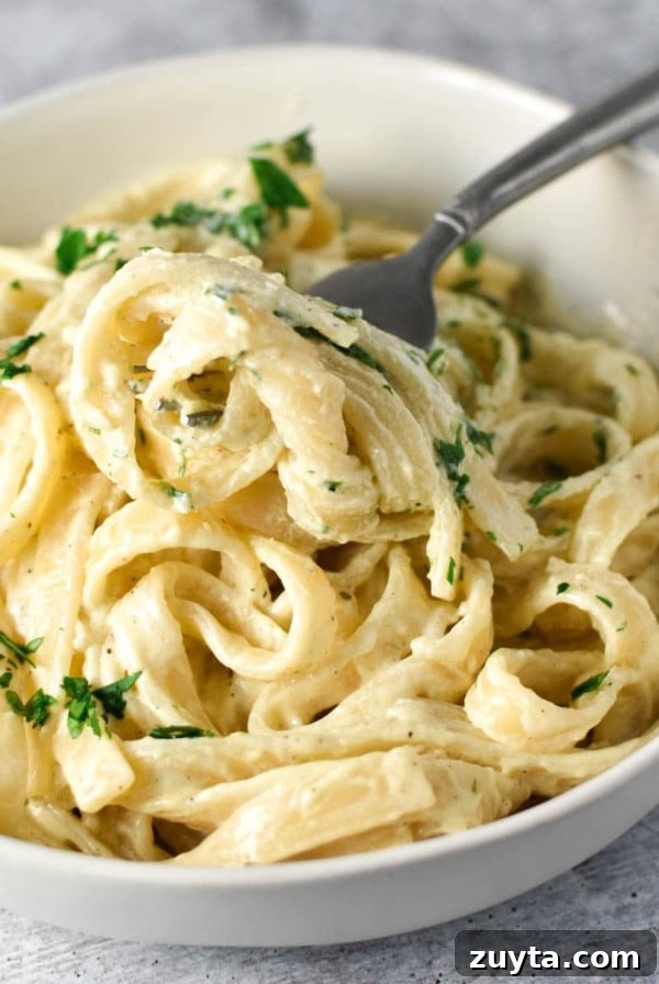 Boursin pasta topped with parsley with a fork in a white bowl.