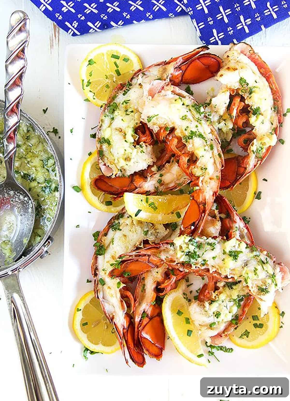 Garlic butter sauce in a saucepan next to a plate of grilled lobster tails.