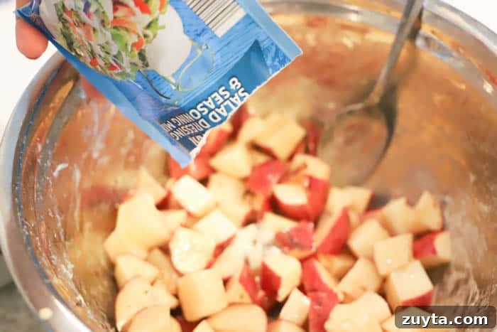Slow Cooker Cheesy Ranch Potatoes Recipe 3 adding ranch seasoning to the bowl for Slow Cooker Cheesy Ranch Potatoes