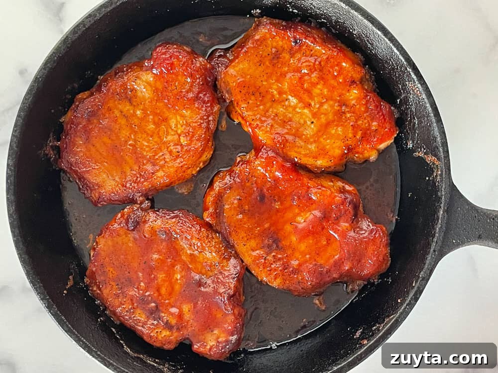 Foolproof Pork Chop Recipes for Juicy Weeknight Dinners 16 Pork chops in a cast iron skillet with bbq sauce on the chops.