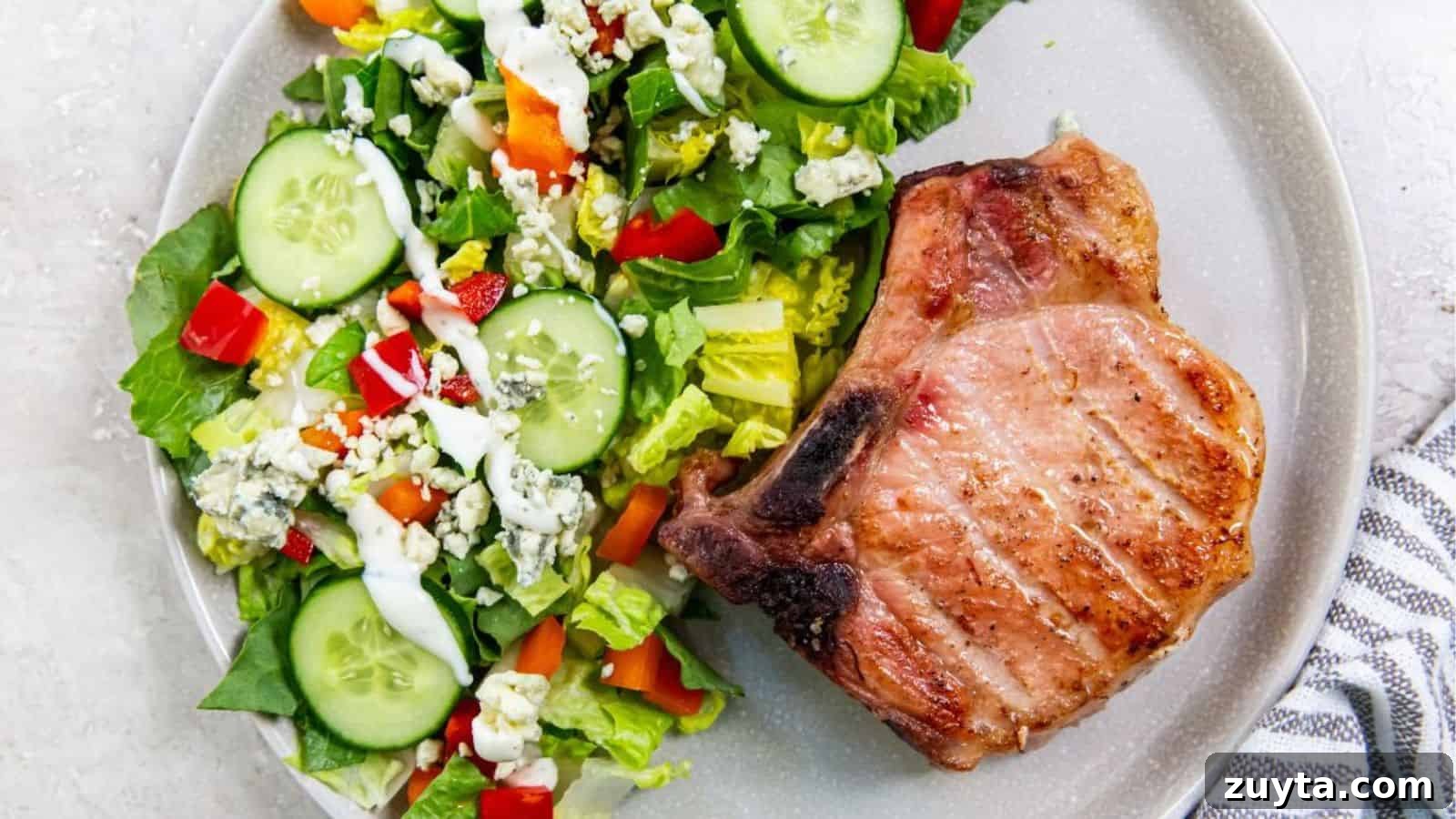 Foolproof Pork Chop Recipes for Juicy Weeknight Dinners 5 Traeger Smoked Pork Chop with a salad on a light gray plate