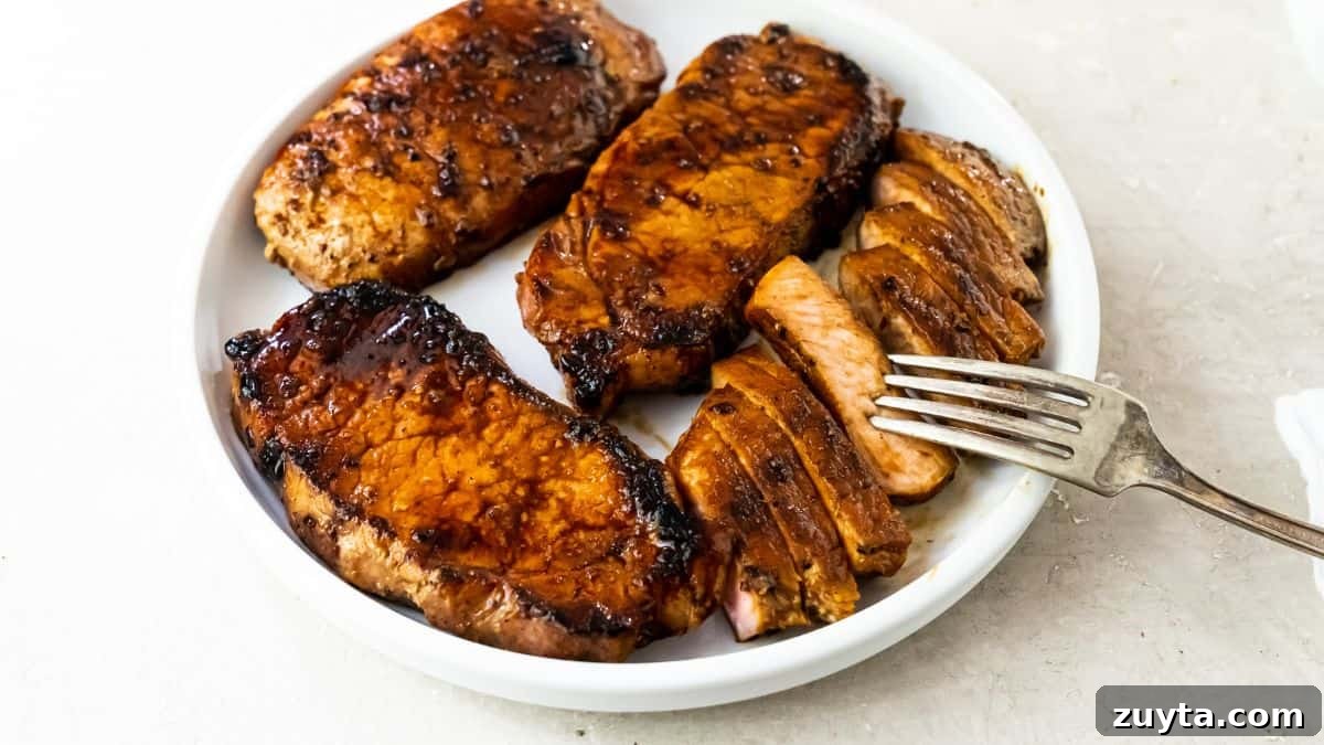 Foolproof Pork Chop Recipes for Juicy Weeknight Dinners 7 Pork Chops on the Blackstone Griddle on a white plate with a fork.