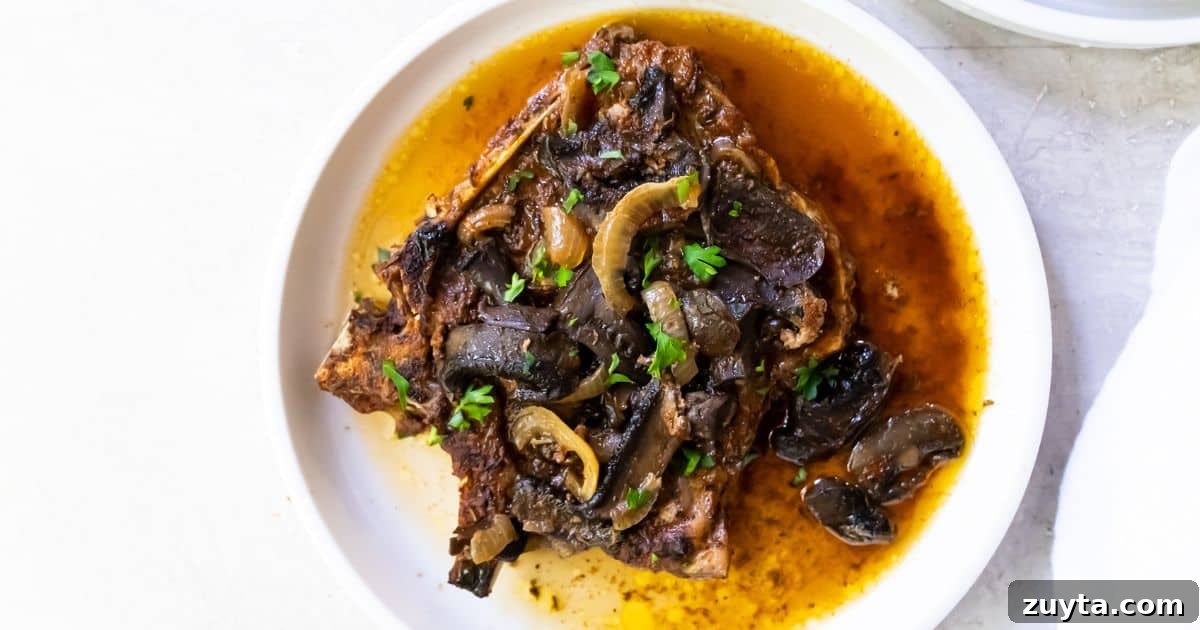 Foolproof Pork Chop Recipes for Juicy Weeknight Dinners 8 Easy Keto Crockpot Pork Chops with mushrooms, onions and parsley on a white plate.