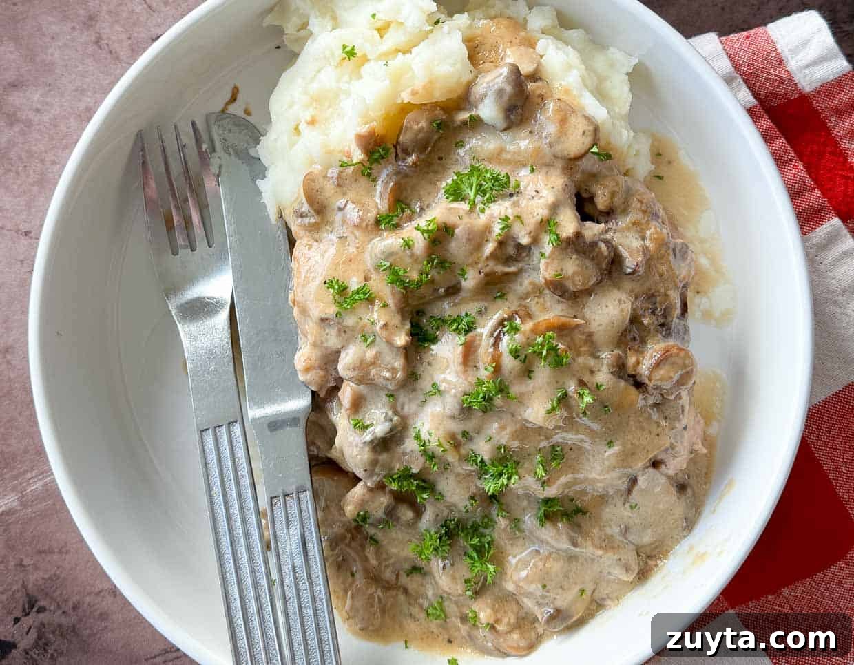 Foolproof Pork Chop Recipes for Juicy Weeknight Dinners 9 A bite of pork chops, mushrooms, and gravy on a fork.