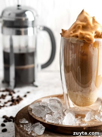 Iced coffee with condensed milk in a tall glass on a wooden plate
