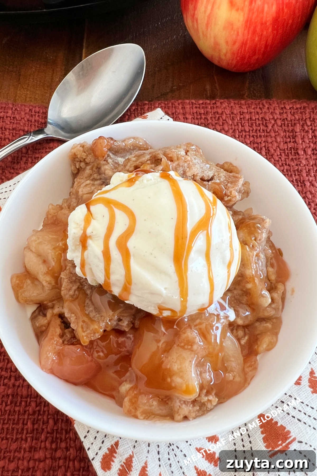 slow cooker apple cobbler with vanilla ice cream and caramel in bowl