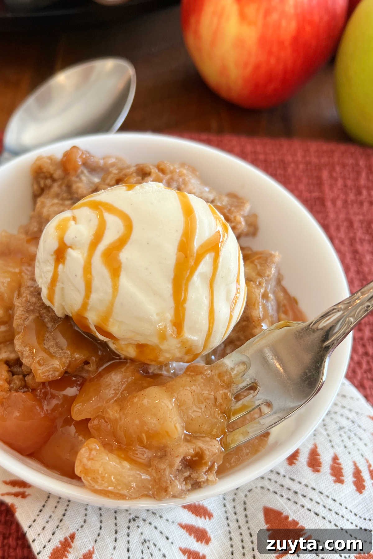 crock pot apple cobbler with ice cream and caramel on fork