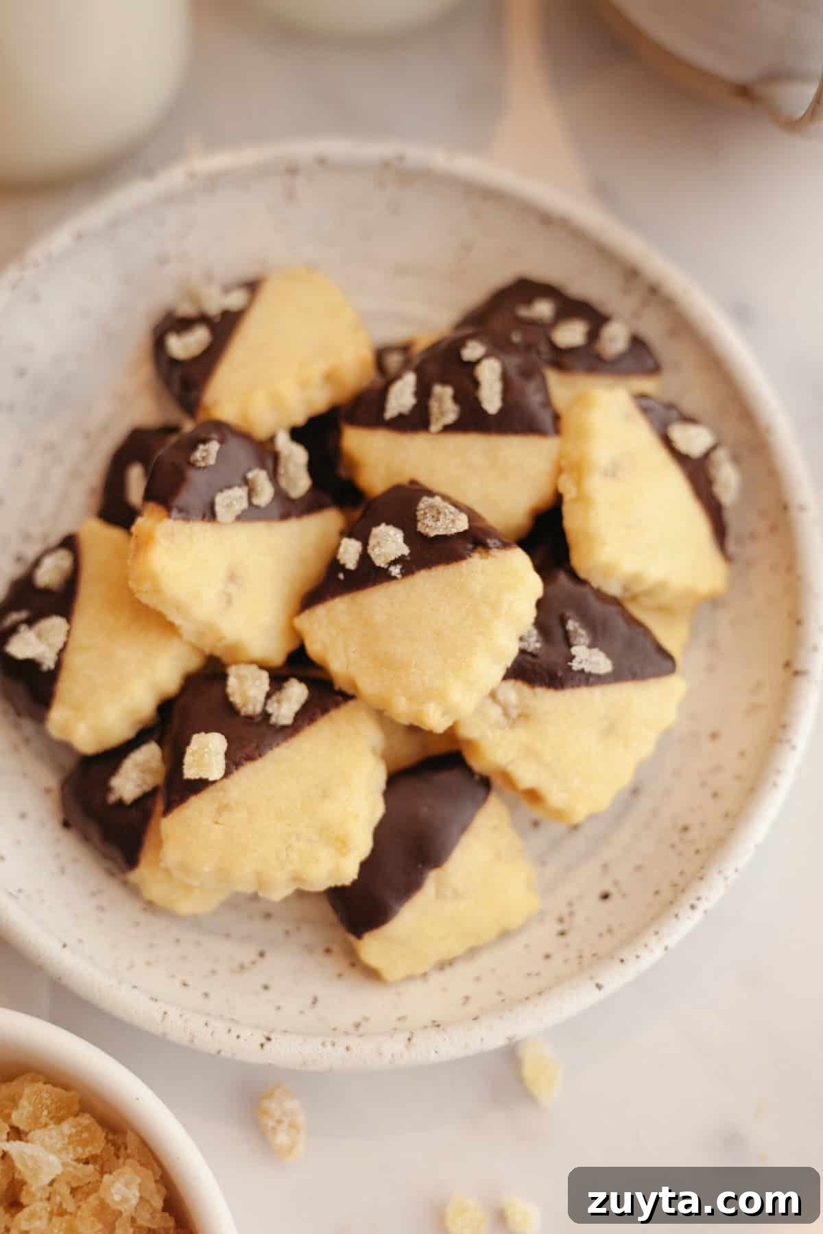 Double-Ginger Shortbread Cookies Recipe 11 A plate full of small ginger shortbread cookies, half dipped in chocolate.
