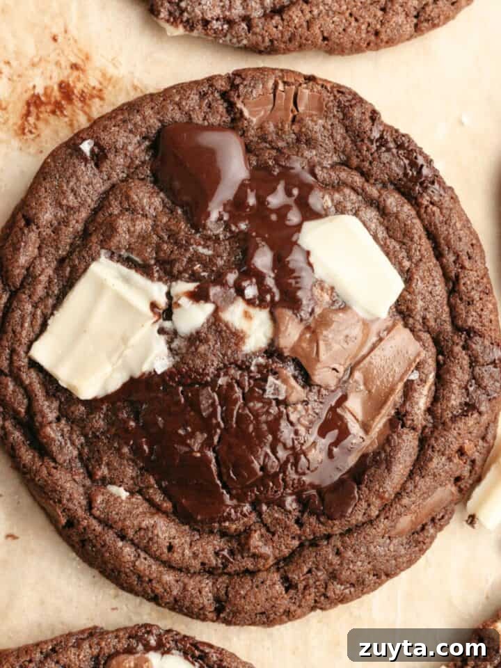 A close up of a triple chocolate chunk cookie on brown parchment paper.