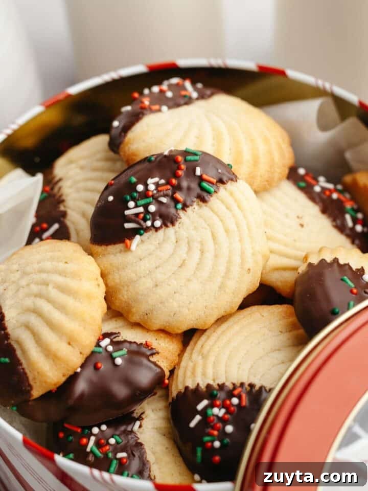 Chocolate dipped butter cookies with sprinkles in a tin.