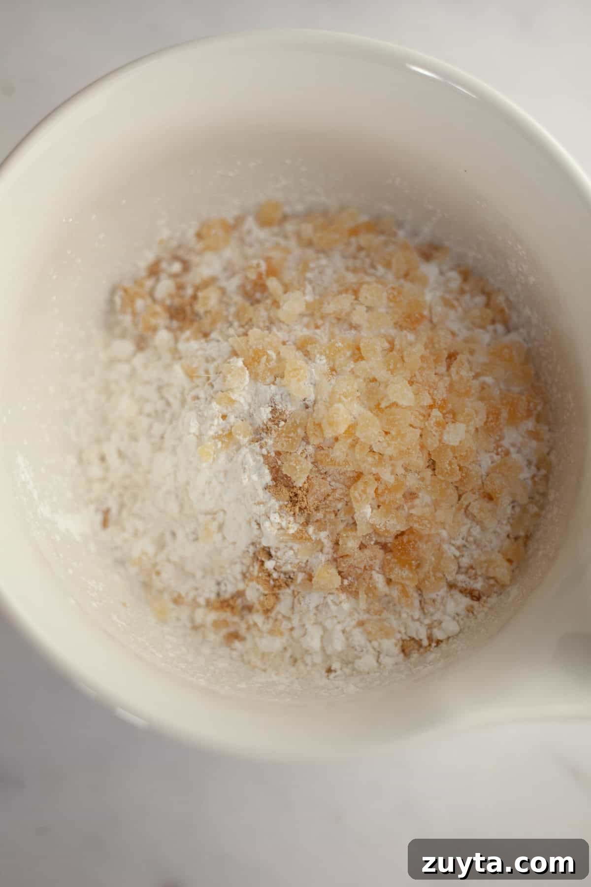 Double-Ginger Shortbread Cookies Recipe 5 A white bowl with flour and chopped crystallized ginger.