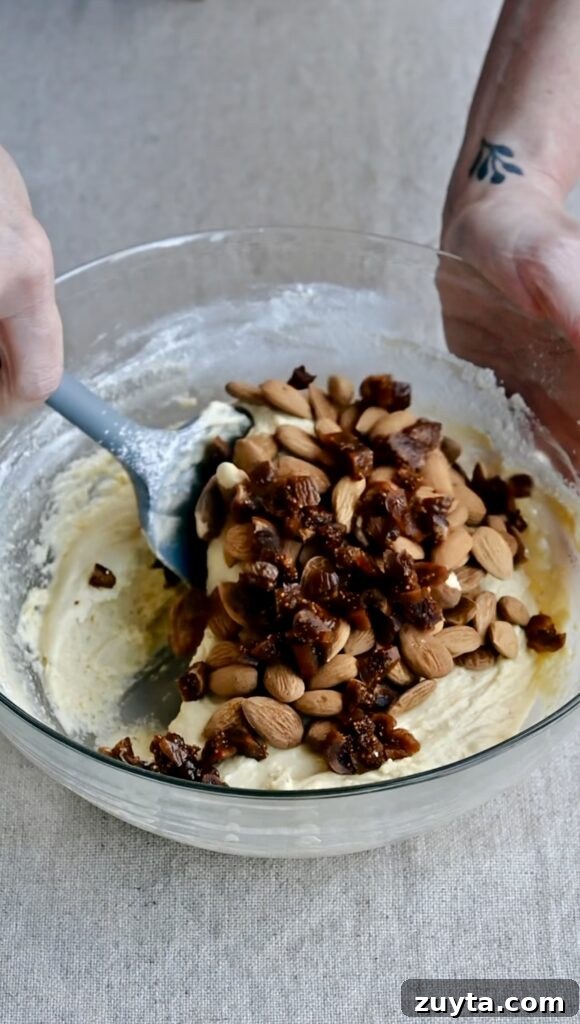 Crisp Fig and Almond Biscotti Recipe 5 A silicone spatula folding almonds and figs into biscotti dough.