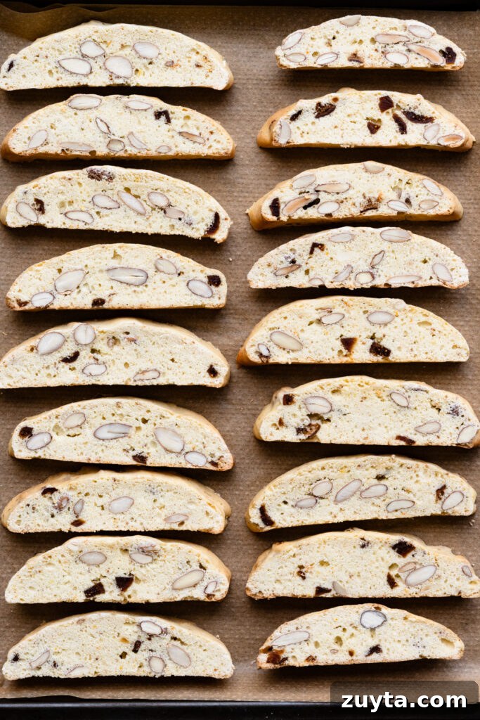 Crisp Fig and Almond Biscotti Recipe 9 Overhead of sliced almond biscotti cookies in two rows on a baking sheet.