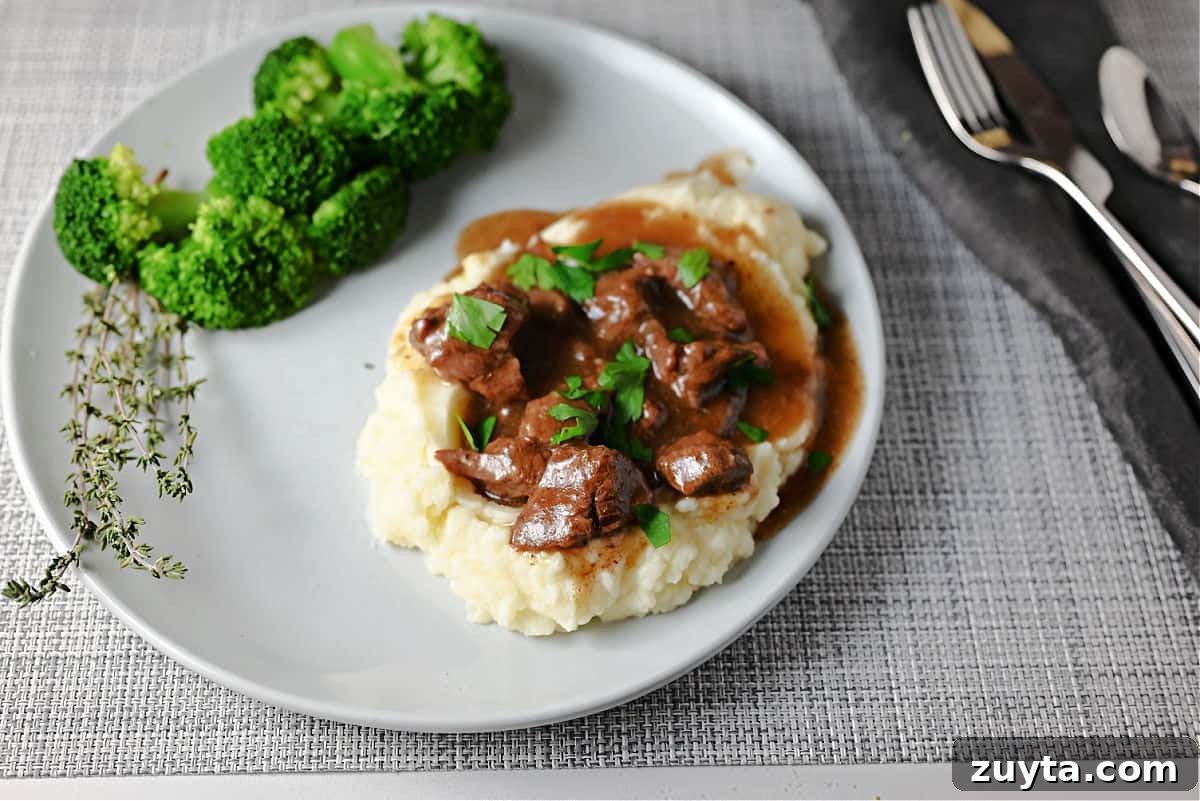 Beef tips and gravy on potatoes served with broccoli.