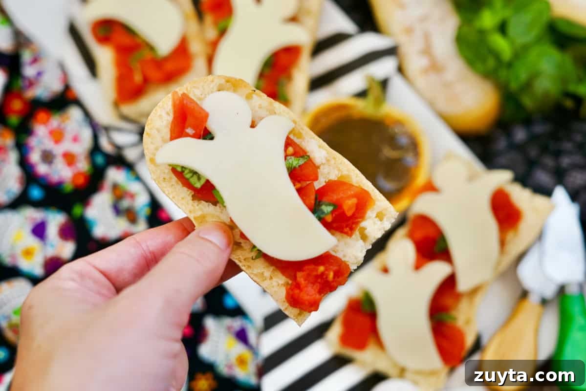 Boo-schetta: Spooky Halloween Bruschetta Appetizer 5 ghost shaped cheese over bruschetta with hand holding
