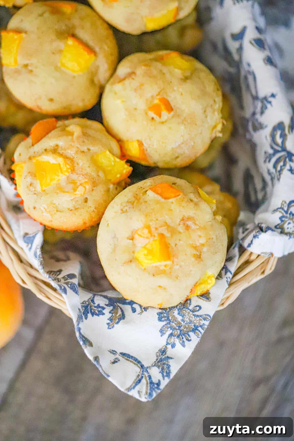 Peach Muffins with Crumble Topping Recipe 2 fresh peach muffins with crumble tops on a cooling rack