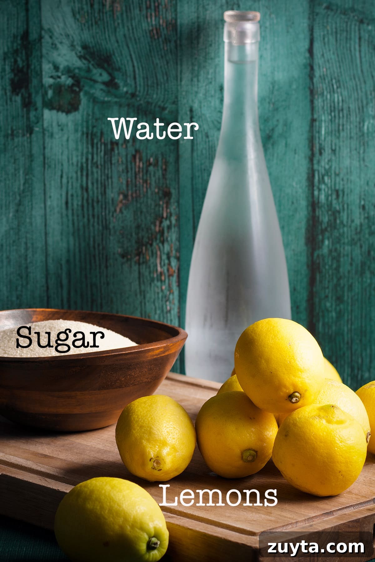 How to Make Candied Lemon Slices for Garnish and Snacks 3 A bowl of sugar, several fresh lemons, and a pitcher of water on a table.