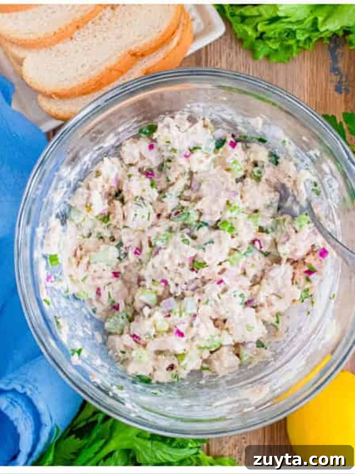 How to Make a Classic Tuna Salad Sandwich 3 Tuna salad mixed together in a glass bowl with celery, onion, and herbs.
