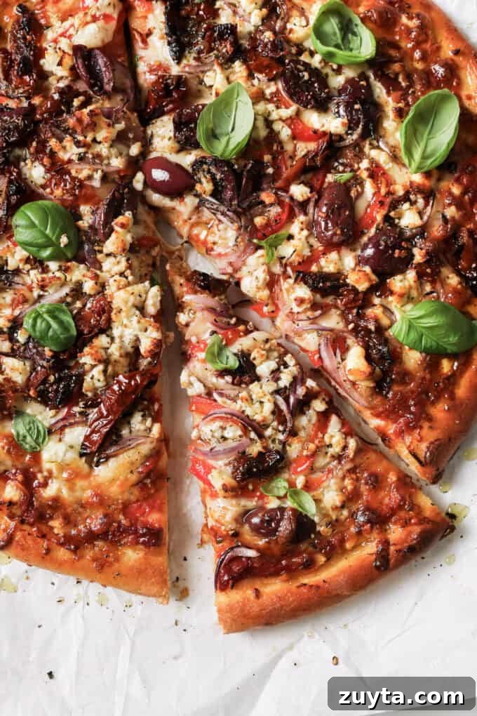 sliced mediterranean pizza topped with fresh basil leaves