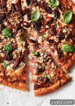 sliced mediterranean pizza topped with fresh basil leaves