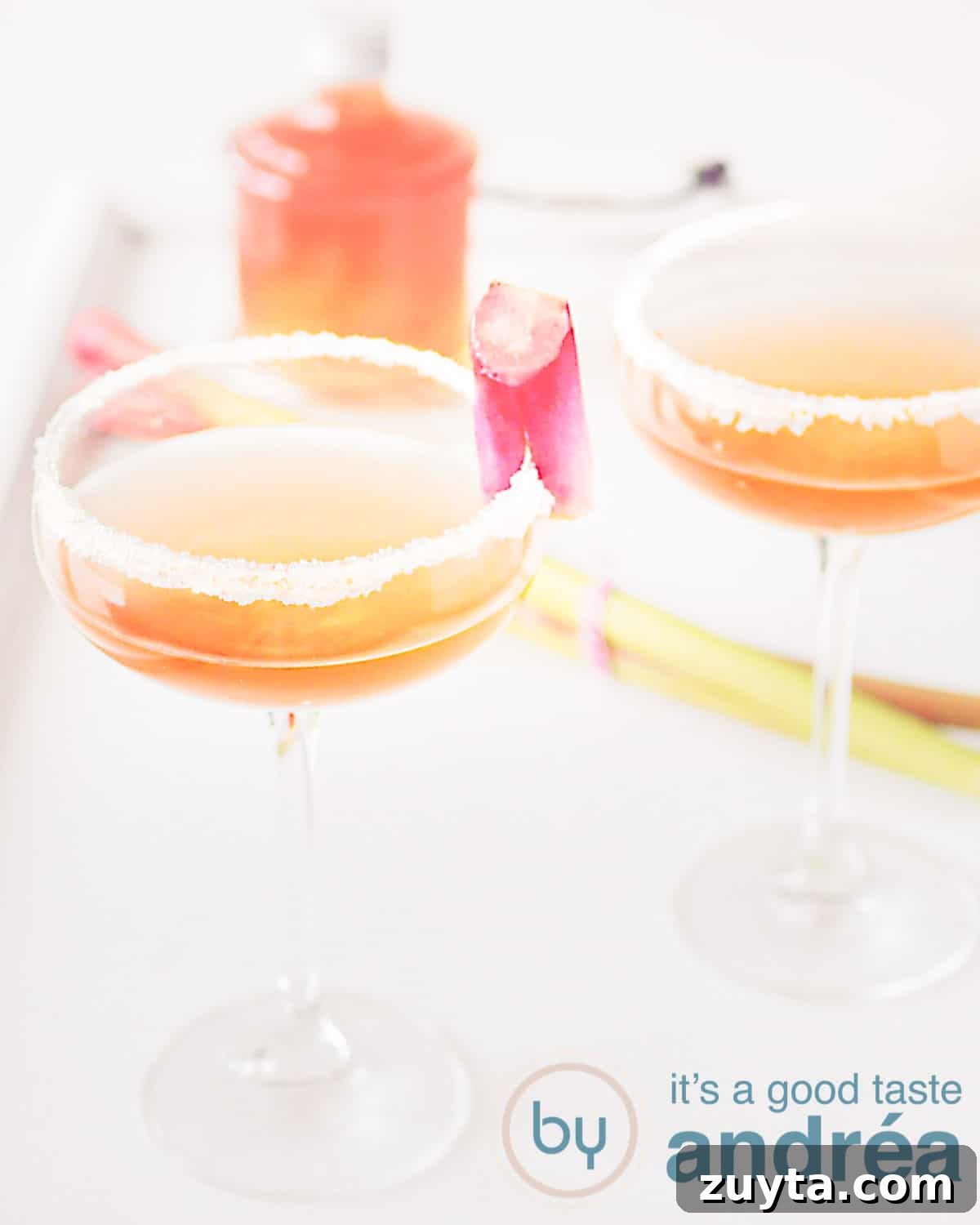 Sparkling Rhubarb Champagne Cocktail Recipe 2 two glasses Rhubarb champagne cocktail with rhubarb syrup in the background
