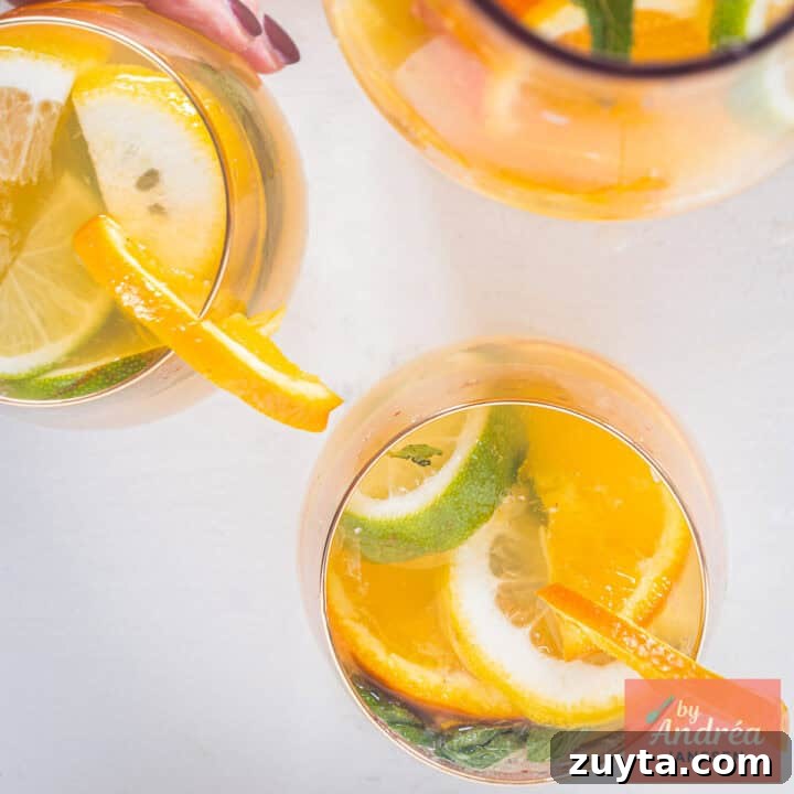A square picture: Homemade orange iced tea with lemon and lime wedges, mint and ice cubes in a glass