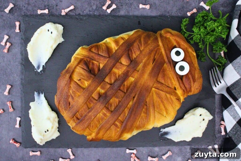 overhead view of mummy meatloaf on a black slate with ghost mashed potatoes and parsley