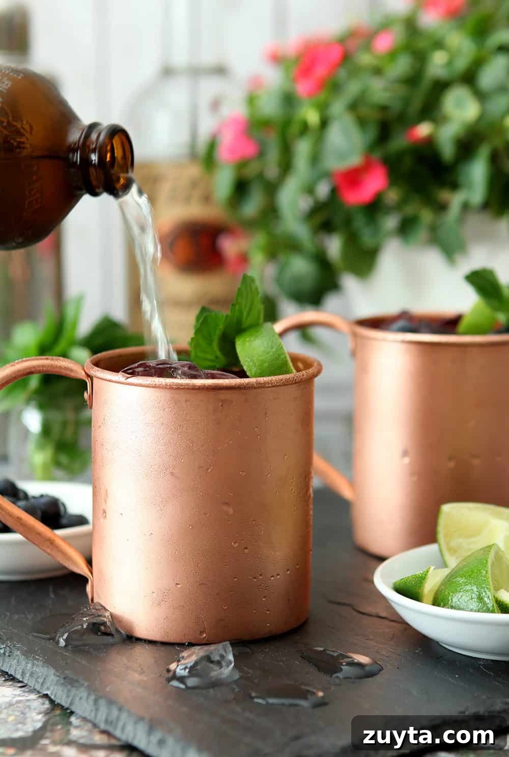 Blueberry Mint Moscow Mule Cocktail Recipe 2 Blueberry Mint Moscow Mule made with ginger beer is served in a chilled copper mug and garnished with mint.