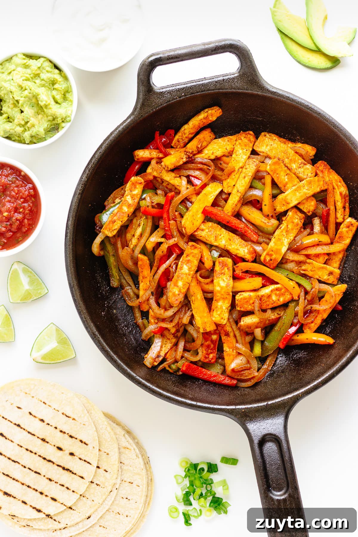 Grilled Halloumi Fajitas with Peppers and Lime 2 Flat lay of halloumi vegetable fajita mixture in a cast iron skillet surrounded by tortillas and toppings.