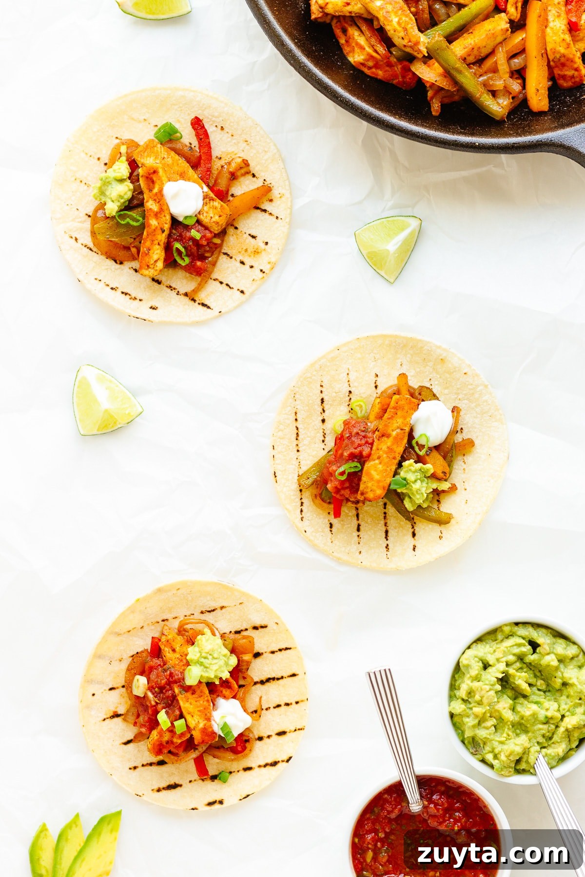 Grilled Halloumi Fajitas with Peppers and Lime 10 Three topped halloumi vegetable fajitas with a skillet of the mixture and toppings around them.