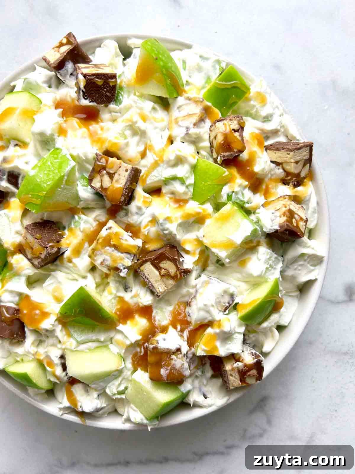 Snickers Salad Recipe: Creamy No-Bake Dessert with Apples 2 bowl of Snickers salad with caramel drizzled on top.