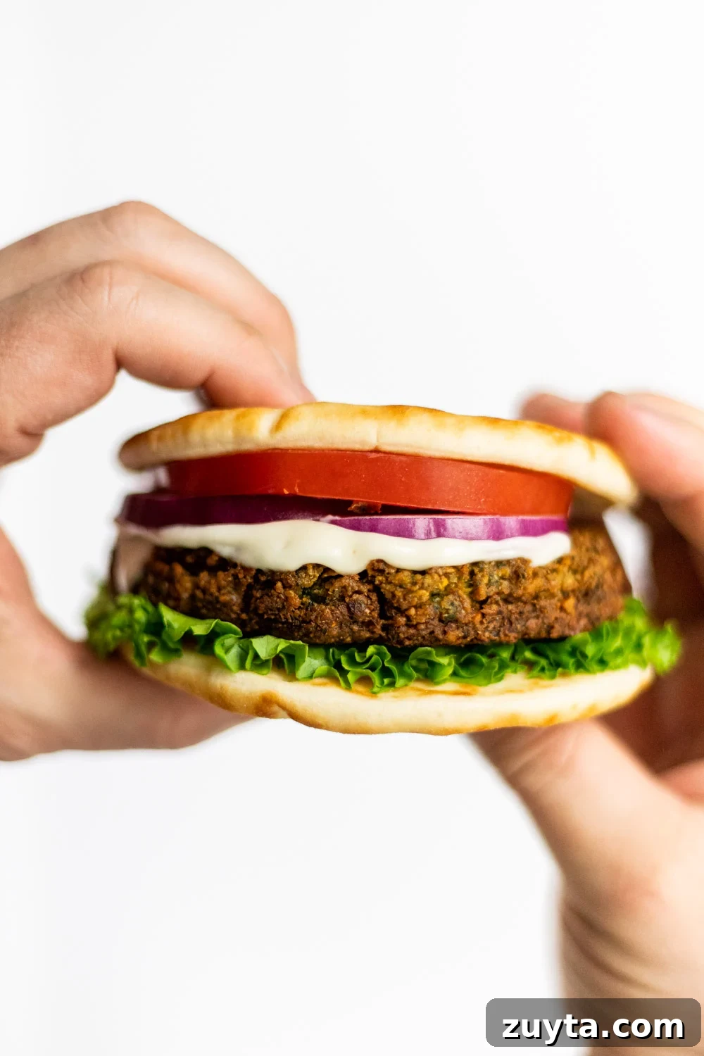 hands holding up a falafel burger
