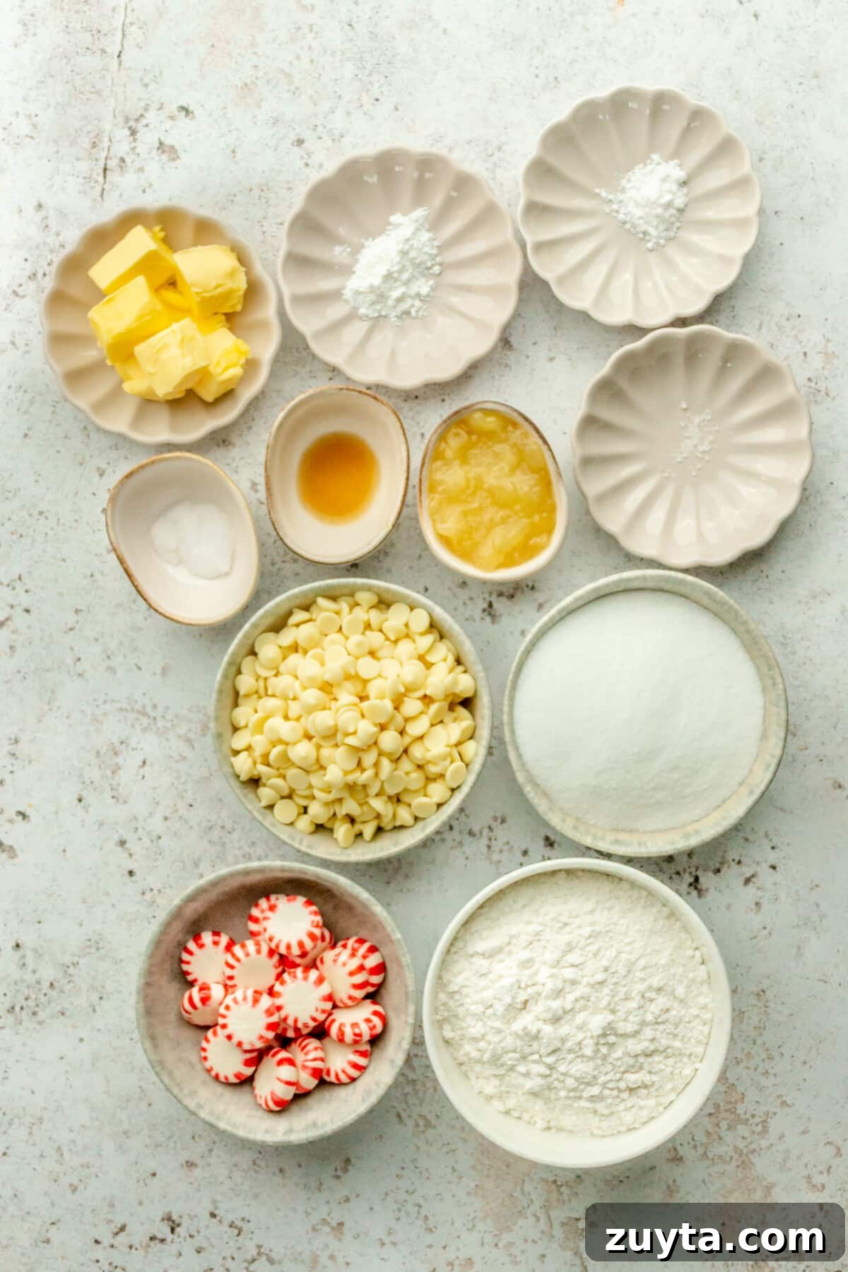White Chocolate Peppermint Icebox Cookies Recipe 2 Ingredients for white chocolate peppermint icebox cookies sit in a variety of bowls and plates on a light grey surface.