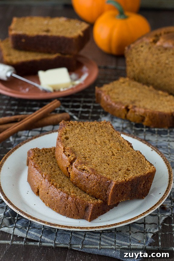 This Pumpkin Pound Cake recipe tastes just like Starbucks Pumpkin Pound Cake - takes 15 minutes to prep! Can be made in muffin, mini muffin or mini loaf pans. Two slices of pumpkin bread on a small white serving plate on a cooling rack.