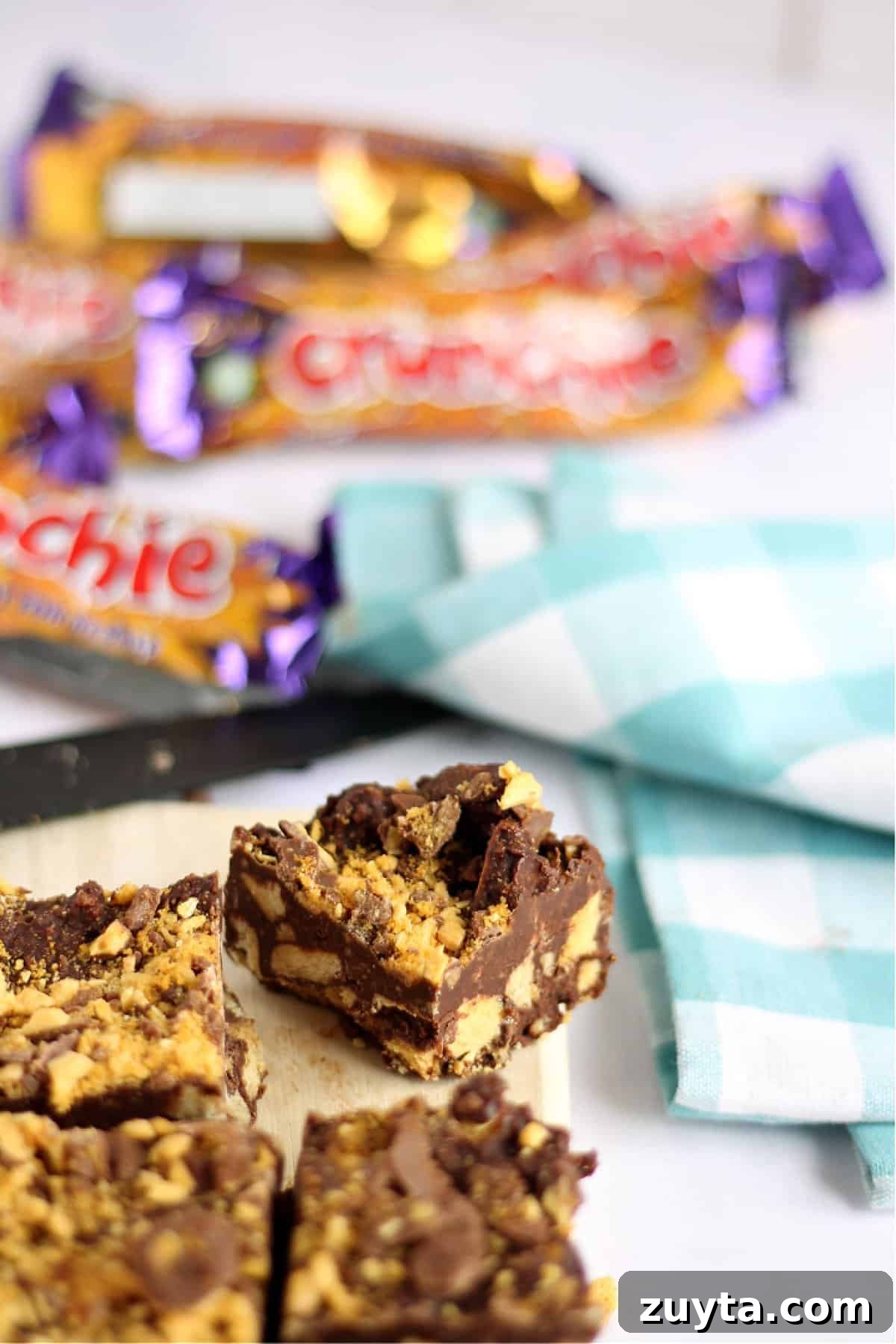 No-Bake Honeycomb Crunchie Tiffin Recipe 2 A slice of crunchie tiffin in focus, with crunchie wrappers in background.