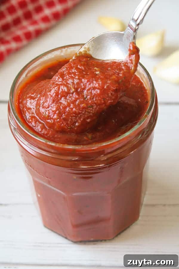 Thick No-Cook Homemade Pizza Sauce 2 Easy & Thick Pizza Sauce being spooned out of a jar