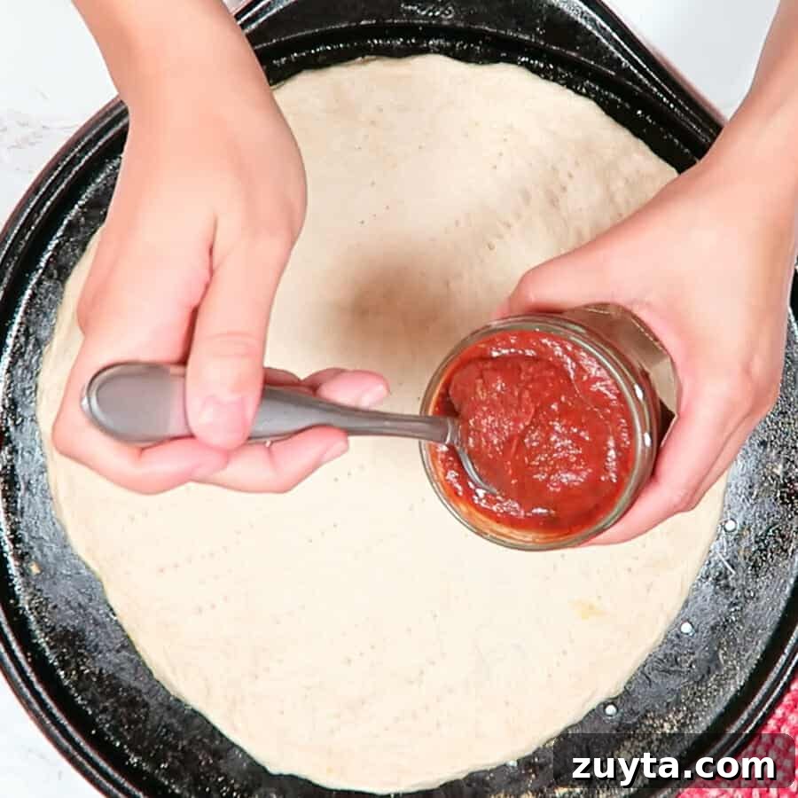 Thick No-Cook Homemade Pizza Sauce 3 Easy & Thick Pizza Sauce being placed on a pizza crust