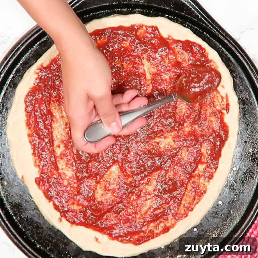 Thick No-Cook Homemade Pizza Sauce 4 Easy & Thick Pizza Sauce being placed on a pizza crust