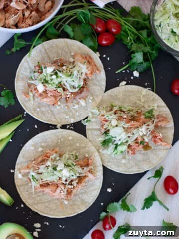 3 rotisserie chicken tacos being served on soft shells.