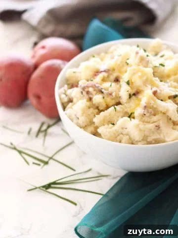 White bowl containing homemade mashed potatoes topped with chives.