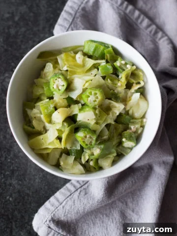 White bowl containing cabbage and okra on black granite counter.